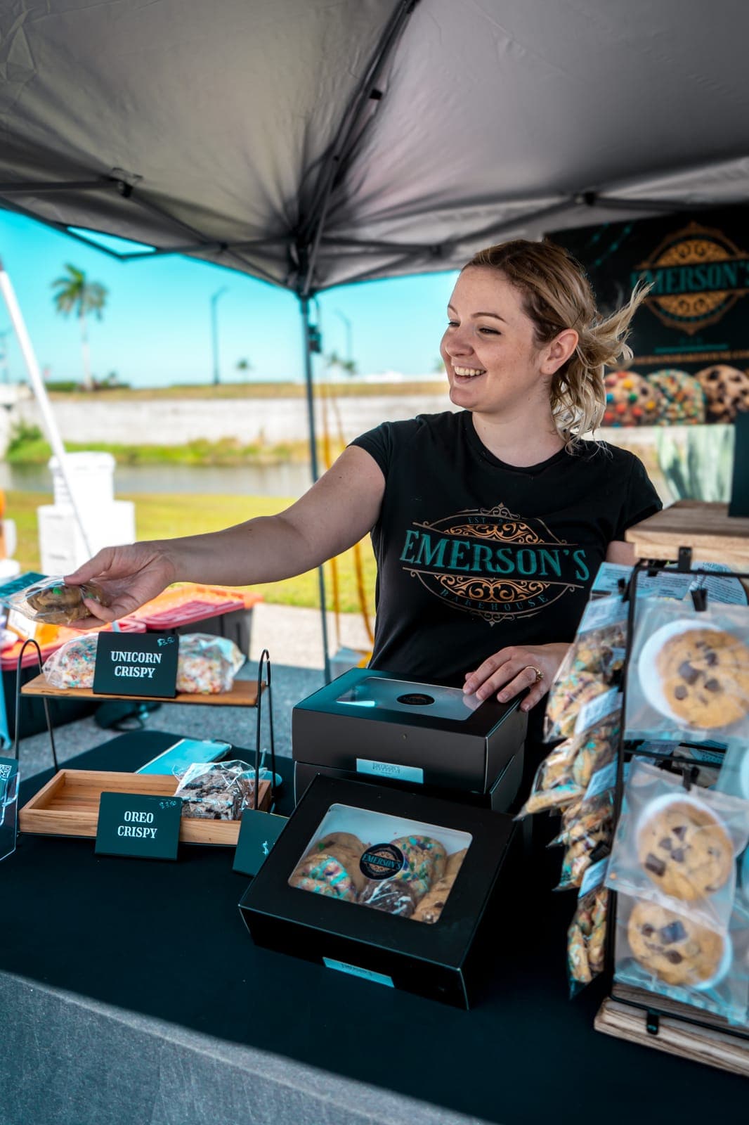 Sarah handing a bagged cookie to a customer at the Emerson's Bakehouse market booth