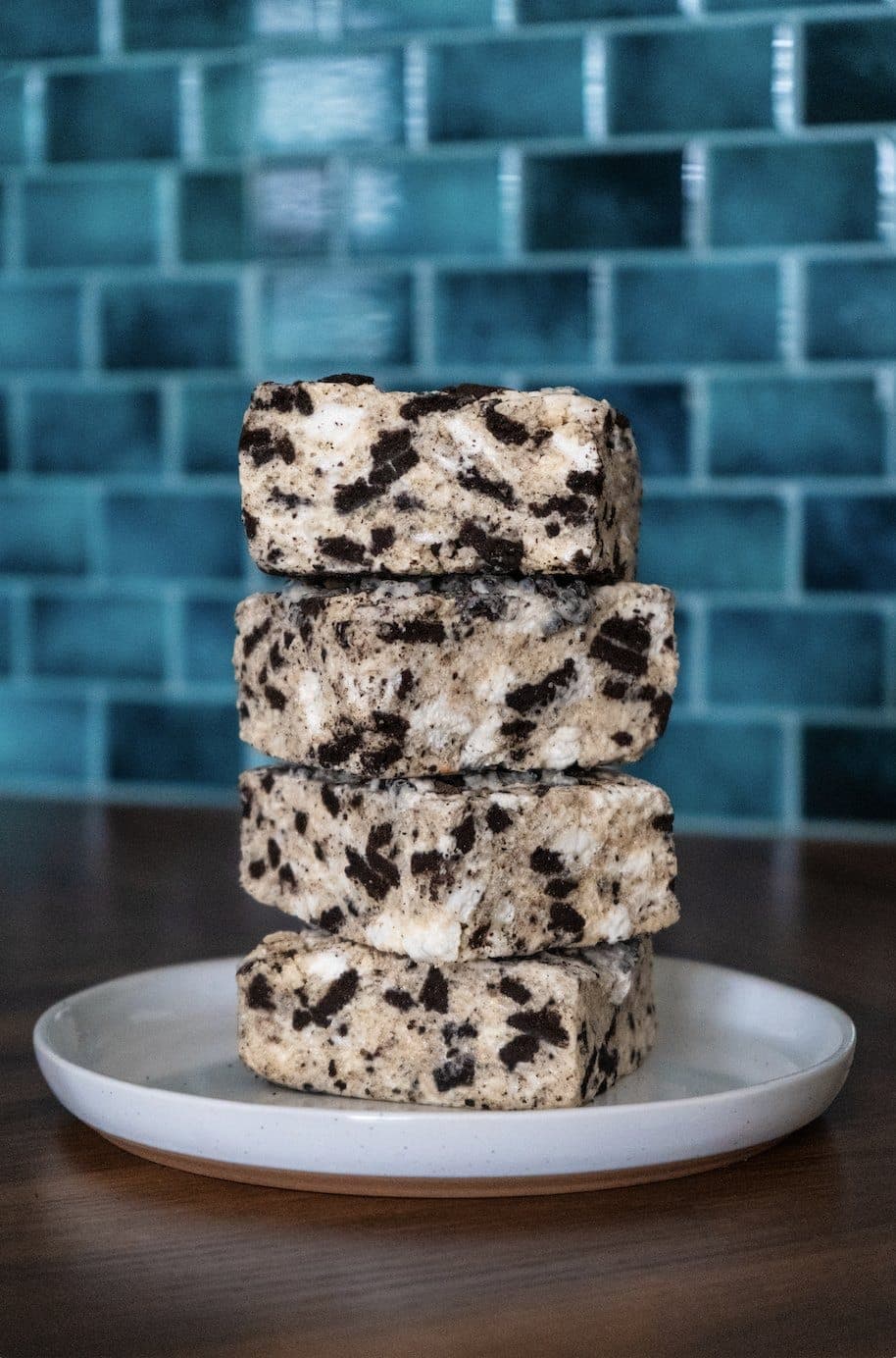 Four Oreo Crispies stacked in front of teal tile