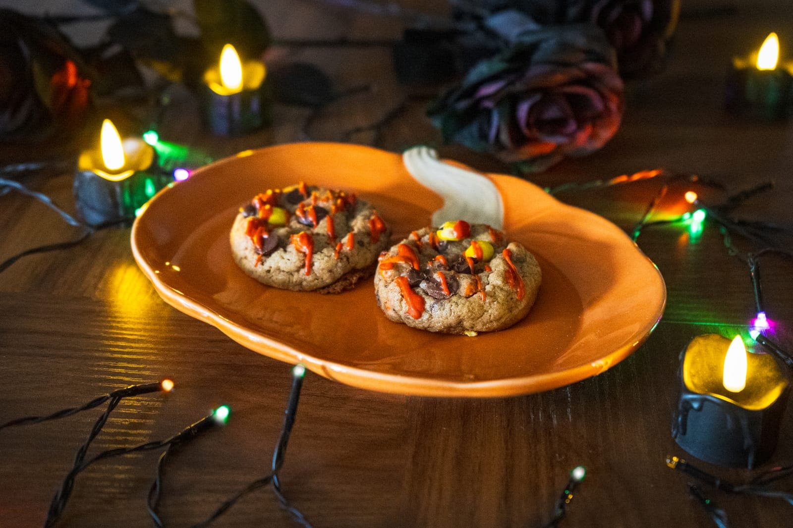 Two Bloody Reese’s cookies with red drizzle and Reese’s Pieces on a pumpkin plate