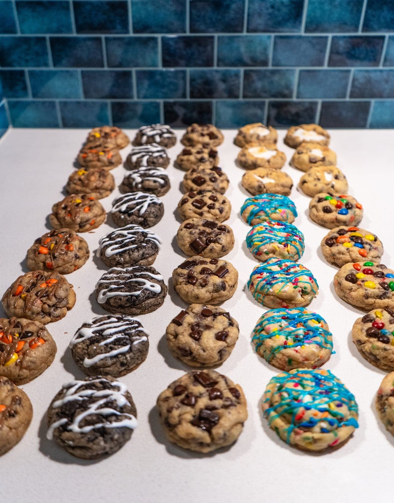 Rows of assorted mini cookies lined up on a white counter